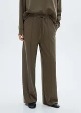 Pantalón de jogging color verde oliva, de corte ancho y tiro medio, con cintura elástica ajustable con cordón. Presenta costuras verticales decorativas en el frente y bolsillos laterales.