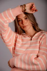 Buzo de punto color salmón con rayas horizontales blancas, cuello alto con cierre frontal parcial y mangas largas.
