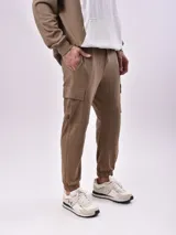 Pantalón de jogging color marrón con bolsillos laterales tipo cargo y puños elásticos.