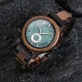 Reloj de pulsera Chenaut modelo Émeraude d’Ébène, con caja y malla de madera de ébano y nogal. Esfera verde esmeralda con segundero pequeño. Cristal Hardlex y movimiento de cuarzo. Resistente al agua (3 ATM).