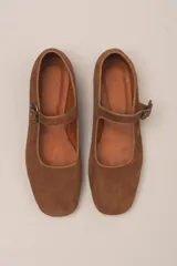 Zapato estilo Mary Jane color marrón, de cuero, con punta redondeada y tira sobre el empeine con hebilla.
