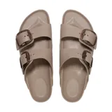 Sandalias tipo 'dos tiras' de material EVA, color topo (marrón claro/beige). Cuentan con dos tiras ajustables con hebillas grandes de plástico con efecto carey/marmolado.