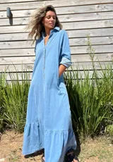 Vestido camisero largo de jean celeste con botones frontales, cuello camisero y volado en el ruedo.