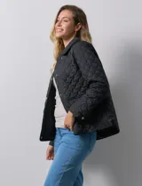 Campera capitoneada negra marca Weatherproof, con cuello con solapa, abertura central con botones metálicos, bolsillos delanteros y forro interno a tono.