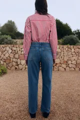 Pantalón de jean azul de corte recto, con tiro alto, cinco bolsillos y cierre con botones.