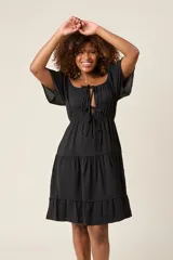 Vestido corto blanco con escote bardot, cintura fruncida y falda escalonada con vuelo.