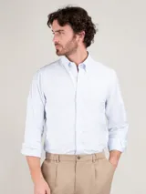 Camisa de hombre a rayas verticales celestes y blancas, corte regular fit, cuello button-down, cierre con botones, manga larga terminada en puño simple y logo bordado en el pecho.