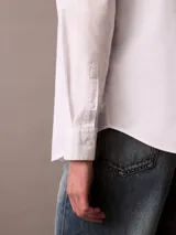 Camisa blanca de manga larga, confeccionada en tejido Oxford de algodón y elastano. Tiene cuello abotonado, cierre frontal con botones y logo de Calvin Klein bordado en el pecho. Corte regular.