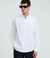 Camisa blanca de corte regular, confeccionada en tejido Oxford de algodón, con cuello inglés, mangas largas y cierre frontal abotonado.