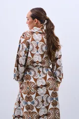 Camisola tipo vestido con estampado floral en tonos marrón, beige y celeste. Tiene cuello camisero, mangas largas y lazo para ajustar en la cintura.