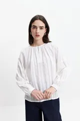 Blusa blanca de manga larga con detalle de tablas en el frente y puños.
