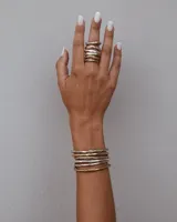 Brazalete rígido abierto de metal color plateado con textura irregular.