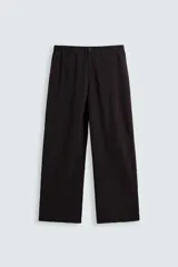 Pantalón marrón oscuro de corte ancho, confeccionado en mezcla de algodón y lino. Presenta cintura elástica, bolsillos laterales y traseros, pliegues frontales y cierre con cremallera y botón.