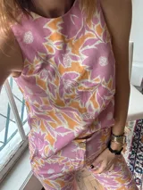 Top sin mangas con estampado floral en tonos rosa y naranja, con cuello redondo y espalda descubierta atada con tres lazos.