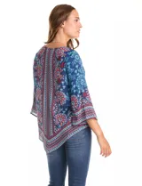 Blusa de gasa con estampado de arabescos y motivos florales en tonos azul marino, rojo y celeste. Presenta cuello redondo y mangas tres cuartos amplias. El bajo es asimétrico, más largo en los laterales.