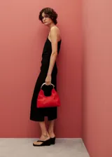 Vestido midi negro de lino con cuello asimétrico y corte recto. Presenta una abertura lateral, cierre de cremallera y cintura drapeada.