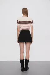Minifalda negra de jean con corte evasé, cintura alta, pinzas delanteras y ruedo desflecado.