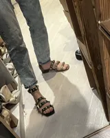 Sandalia de cuero vacuno, color marrón, con hebillas doradas y detalle de perlas.