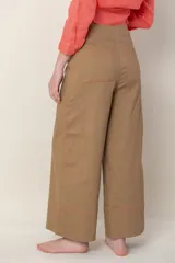 Pantalón ancho color marrón, de tiro alto, con detalle de costuras bordadas en color naranja en ruedo y cintura.