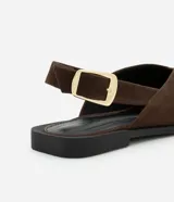 Zapatilla slingback marrón de material sintético con puntera fina, tira media con hebilla lateral dorada y tacón bajo.