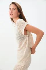 Remera de tejido calado color crudo, de corte recto y mangas cortas.