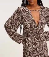 Vestido corto marrón con estampado paisley en blanco, escote en V con abertura y manga larga.