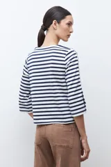 Buzo de cuello redondo con estampado de rayas horizontales blancas y azul marino. Presenta mangas de largo 3/4 con un panel lateral en contraste, botones decorativos y terminación en volados.