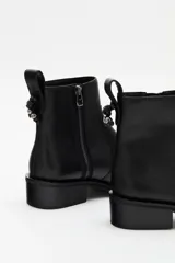 Botas de cuero negras con punta redonda, detalle de tachas en la suela y cierre lateral.