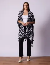 Kimono tejido con estampado geométrico en blanco y negro, ruedo con borlas y composición 100% poliéster.
