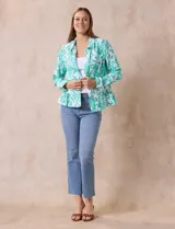 Campera blanca con bordado floral en verde agua, cuello solapa, cierre con botones, bolsillos delanteros y ruedo fruncido.