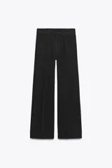 Pantalón de jean negro de corte palazzo, tiro medio y cintura con trabillas. Tiene bolsillos delanteros y traseros, raya planchada en el frente y cierre frontal con cremallera, botón y ganchos metálicos.