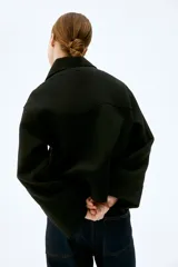 Campera corta negra de tejido de fieltro suave con cuello clásico y cierre frontal con botones. Modelo de corte holgado con hombros caídos y bolsillos insertados adelante.