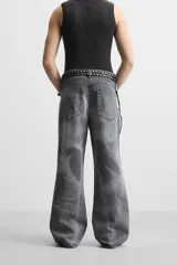 Pantalón de jean gris de corte flare, con cinco bolsillos, lavado con efecto de contraste en las piernas y bajo con acabado irregular.