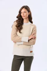 Buzo tejido de abrigo con bloques de color en tonos beige, tostado y blanco. Presenta cuello redondo, mangas largas y un pequeño parche de cuero en el dobladillo inferior.