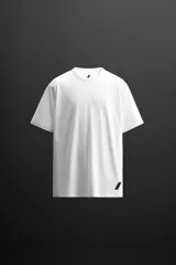 Camiseta blanca de corte holgado confeccionada en tejido de mezcla de algodón. Tiene cuello redondo, mangas cortas y logo estampado en el bajo.