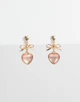 Par de aros colgantes dorados con pasante en forma de corazón, moño y dije de corazón rosa.