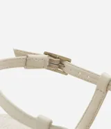 Sandalia femenina confeccionada en material sintético color crema, con punta redonda, tiras finas asimétricas, dedera con detalle bold y hebilla lateral. Prenda con salto mediano fino.