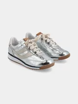 Zapatillas deportivas plateadas con detalles en color crema, cordones y suela marrón.