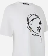 Remera blanca de algodón con cuello redondo y bordado de una cara de mujer con caravana dorada.