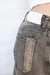 Jean de mujer color gris con efecto acid wash, de corte recto y tiro alto. Incluye bolsillos traseros y etiqueta de marca blanca en la cintura.