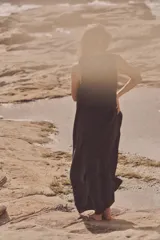 Vestido midi negro de tejido fluido, con cuello redondo y sisa. Cierre trasero con cremallera oculta.
