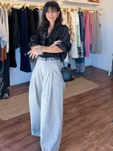 Pantalón de jean celeste de corte ancho con pinzas en la cintura y cinturón plateado con apliques florales.