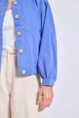 Cazadora color verde oliva con cuello redondo, cierre frontal con botones y mangas largas con puños elásticos.