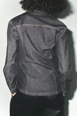 Camisa de denim color gris oscuro, de corte entallado, con cuello solapa, manga larga, dos bolsillos frontales y cierre frontal con botones.