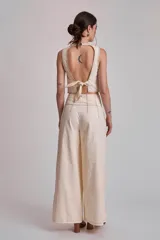 Pantalón negro de tiro alto, corte ancho y largo, con pliegues frontales y pespuntes contrastantes en blanco en la cintura y bolsillos.