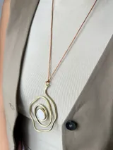 Collar con cordón marrón ajustable y dije dorado con forma de espiral irregular y centro de nácar.