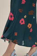 Vestido largo azul marino con estampado de flores en tonos naranja, rosa y celeste. Tiene corte holgado, mangas cortas y bolsillos laterales.