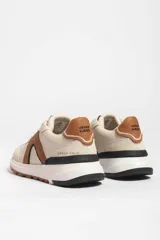 Zapatillas deportivas marrones con detalles en blanco y suela color caramelo.