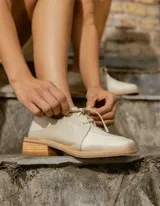 Zapato acordonado de cuero vacuno color marrón oscuro, con suela de goma, horma cuadrada y tacón bajo.