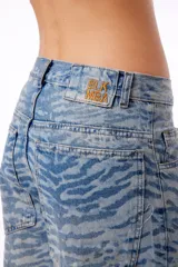 Pantalón de jean oversized de tiro bajo, color azul lavado, con estampado de tigresa grabado con láser.